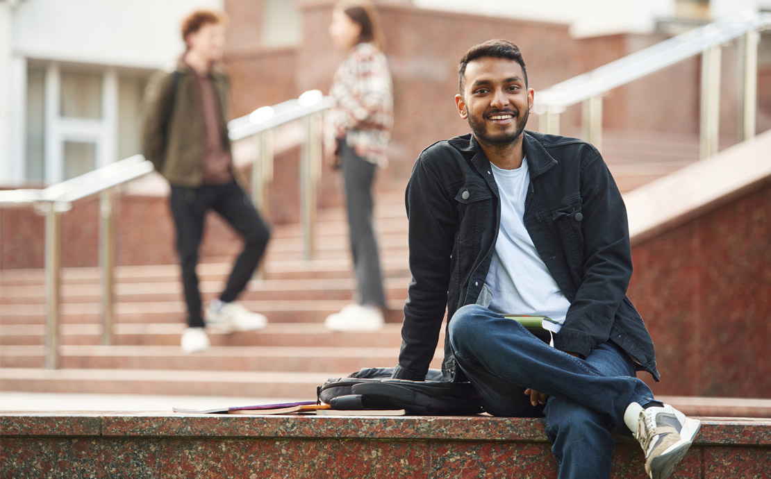A student sitting on a wall smiling