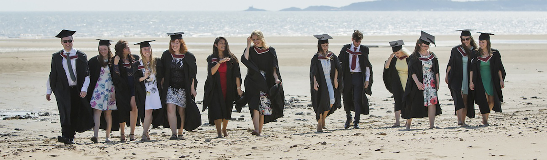 Group of graduates on the beach by the Bay Campus