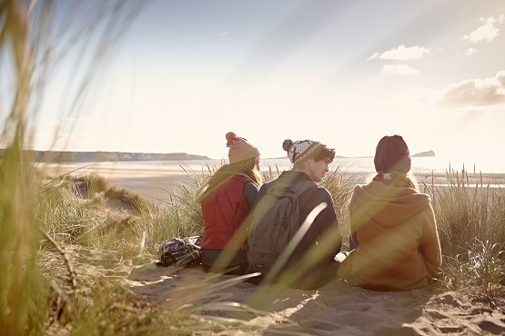 Three students sitting on a beach