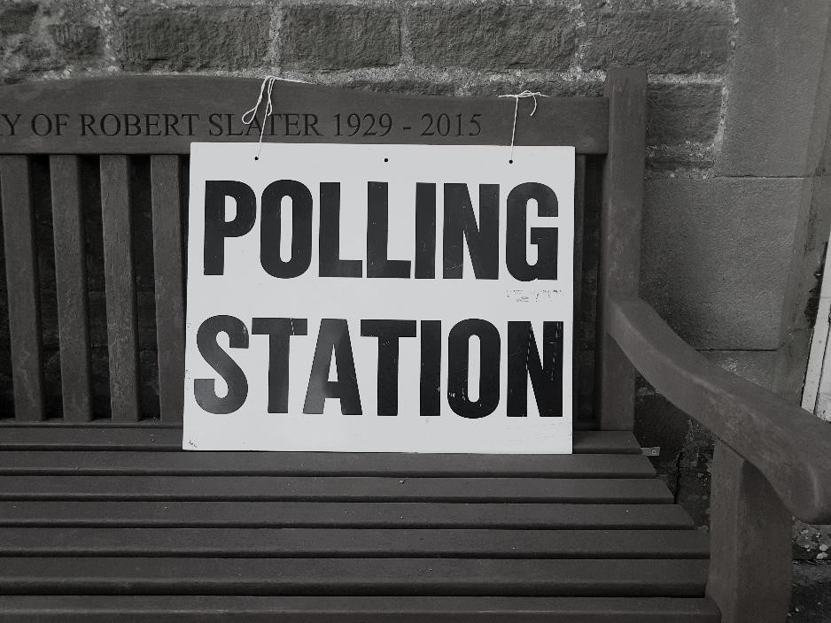 A wooden bench displaying a sign reading 'Polling Station.' 