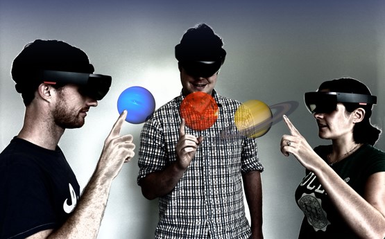 Three students viewing planets at their fingertips using virtual reality headsets