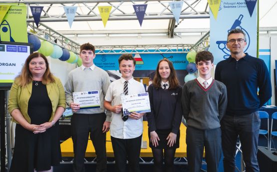 Image of the winner of last year's competition alongside the judges