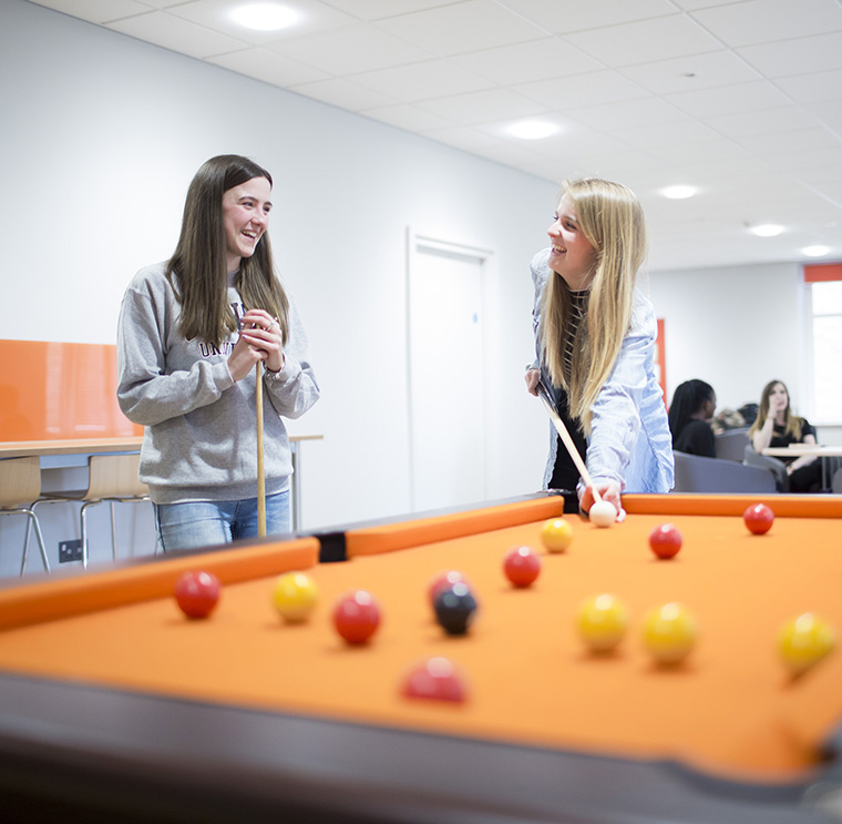 Students playing a game of pool in the social space