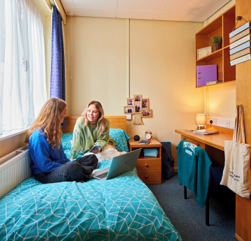 An image of two students sitting and talking in student accommodation on Singleton Campus.