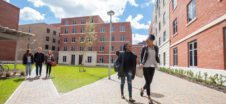 Exterior view of Bay Campus Residences in the sunlight with students walking through