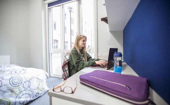 A female student is sat at a desk in her accommodation