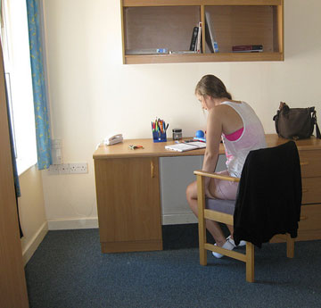 En-suite- bedroom in Beck House, Block F - girl sitting at desk in room with blue carpet and a window