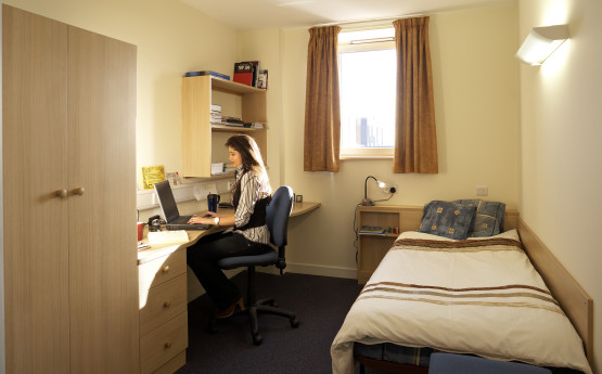 a university bedroom with a student at a desk