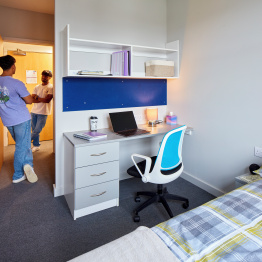 An image of two students talking to each other in a room in student accommodation on Bay Campus.