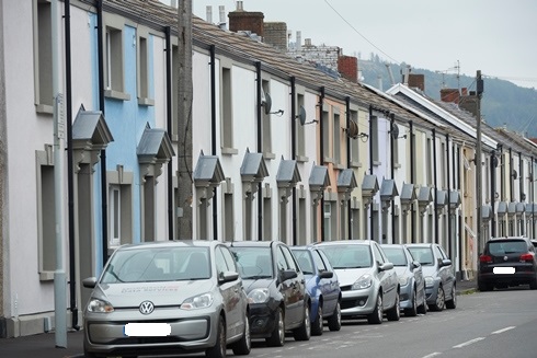 multicoloured houses from otherside of road with cars parked outside