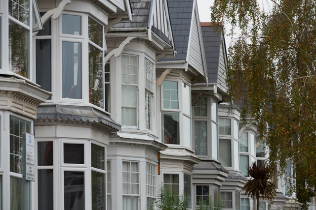 Row of white Victorian bay windows, showing upstairs and partial downstairs windows