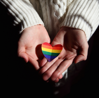 A picture of a person cradling a rainbow coloured paper heart. (Pexels | Sharon McCutcheon)