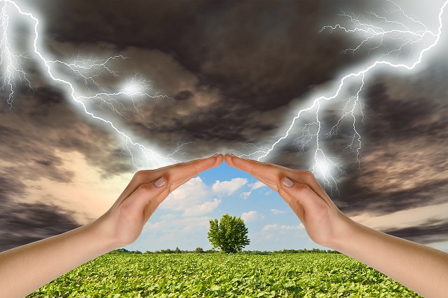 a storm being blacked out by a pair of hands ahead of a sunny field