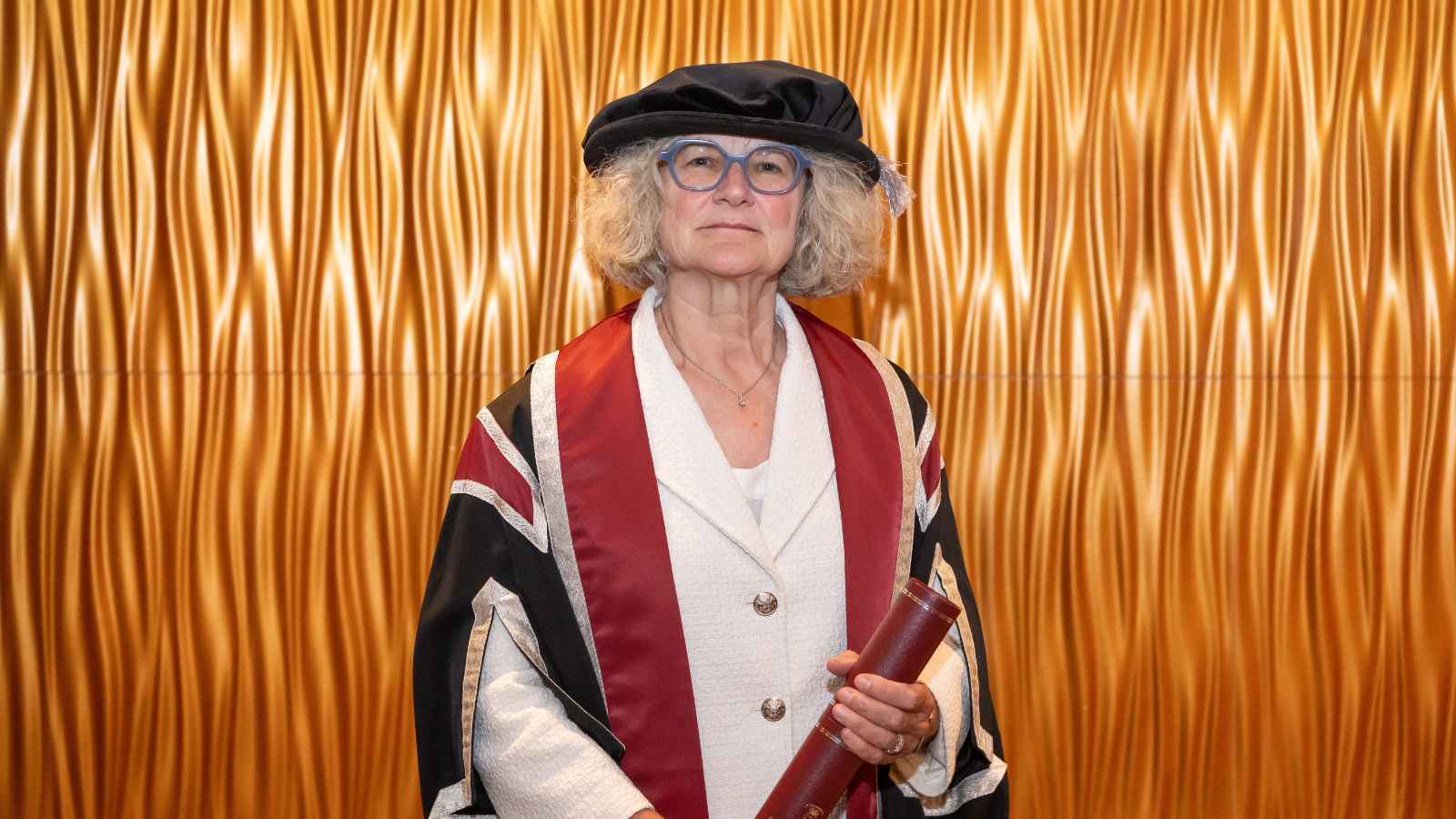 Lady wearing cap & gown smiling at the camera