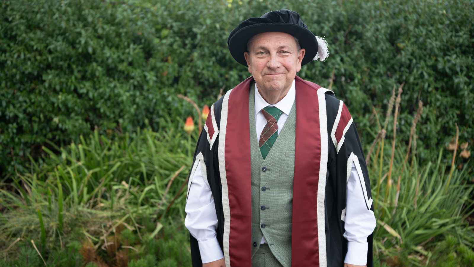 Man wearing cap & gown smiling for the camera