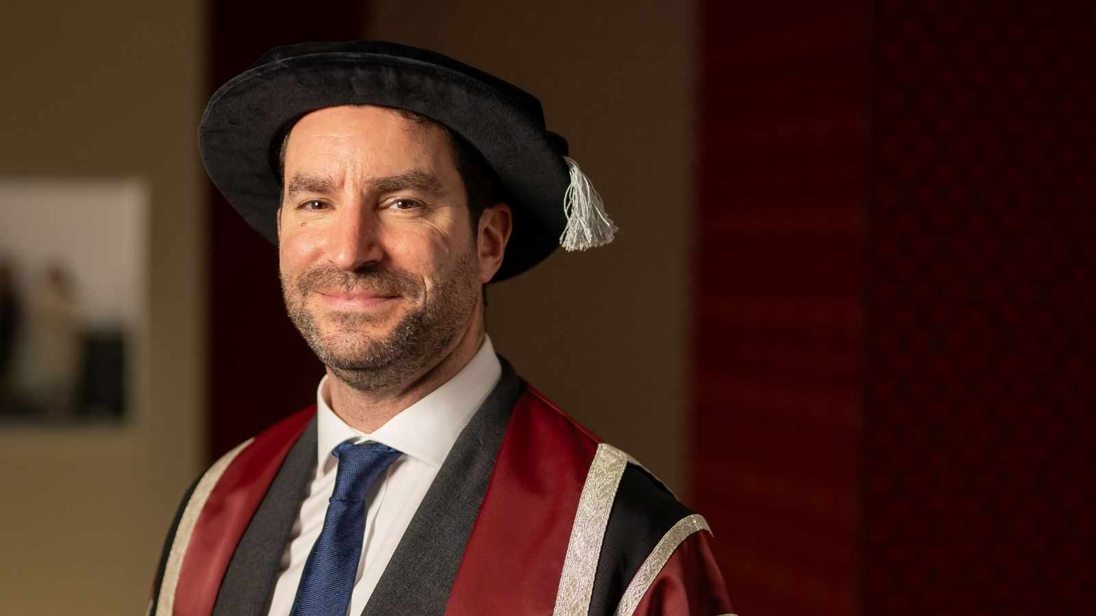 Man wearing cap and gown and smiling at the camera