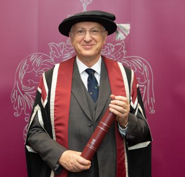 Man in a graduation outfit smiling at the camera
