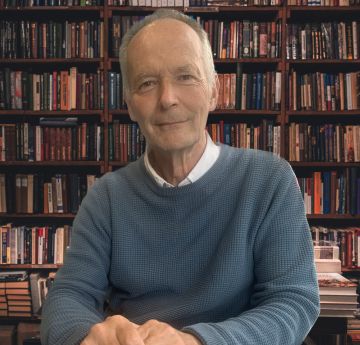 Man sitting at a table with book shelves behind him