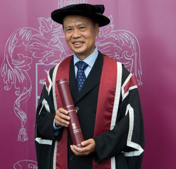 Man wearing cap and gown smiling at the camera