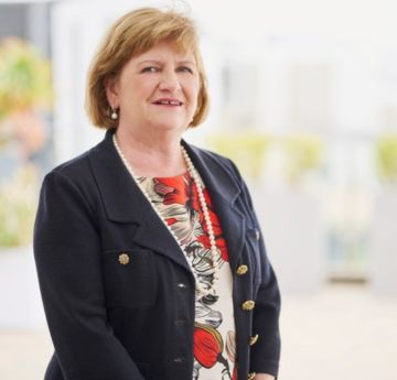 Lady dressed smartly standing outdoors smiling at the camera