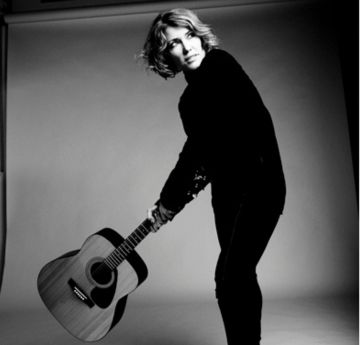 Lady in dark clothing holding a guitar