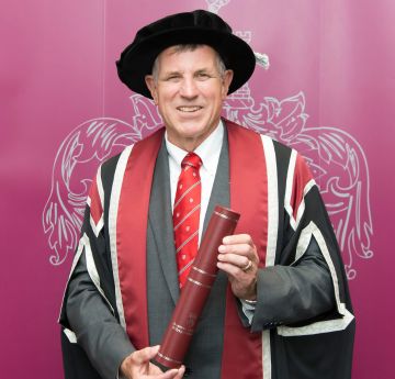 Man in cap and gown smiling at the camera