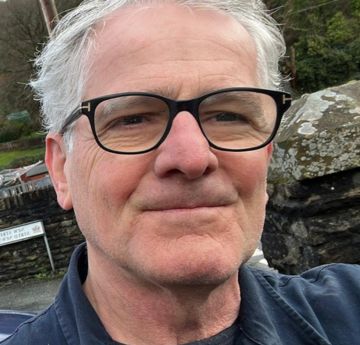 Man with glasses outside smiling at the camera