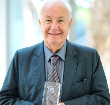 Man in a suit holding an award smiling at the camera