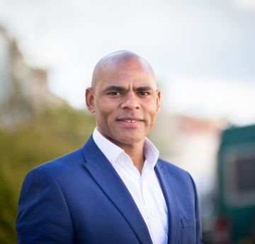 Photo of man in a suit outdoors looking at the camera