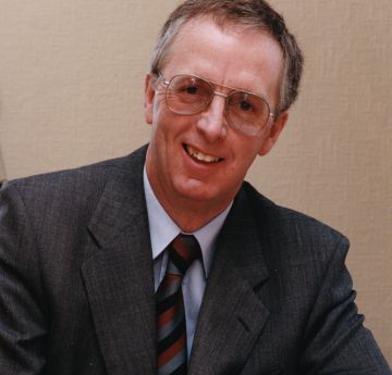 Man wearing a shirt and tie smiling at the camera