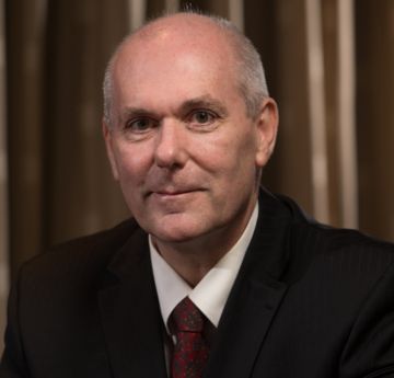 Headshot of man in a suit smiling at the camera