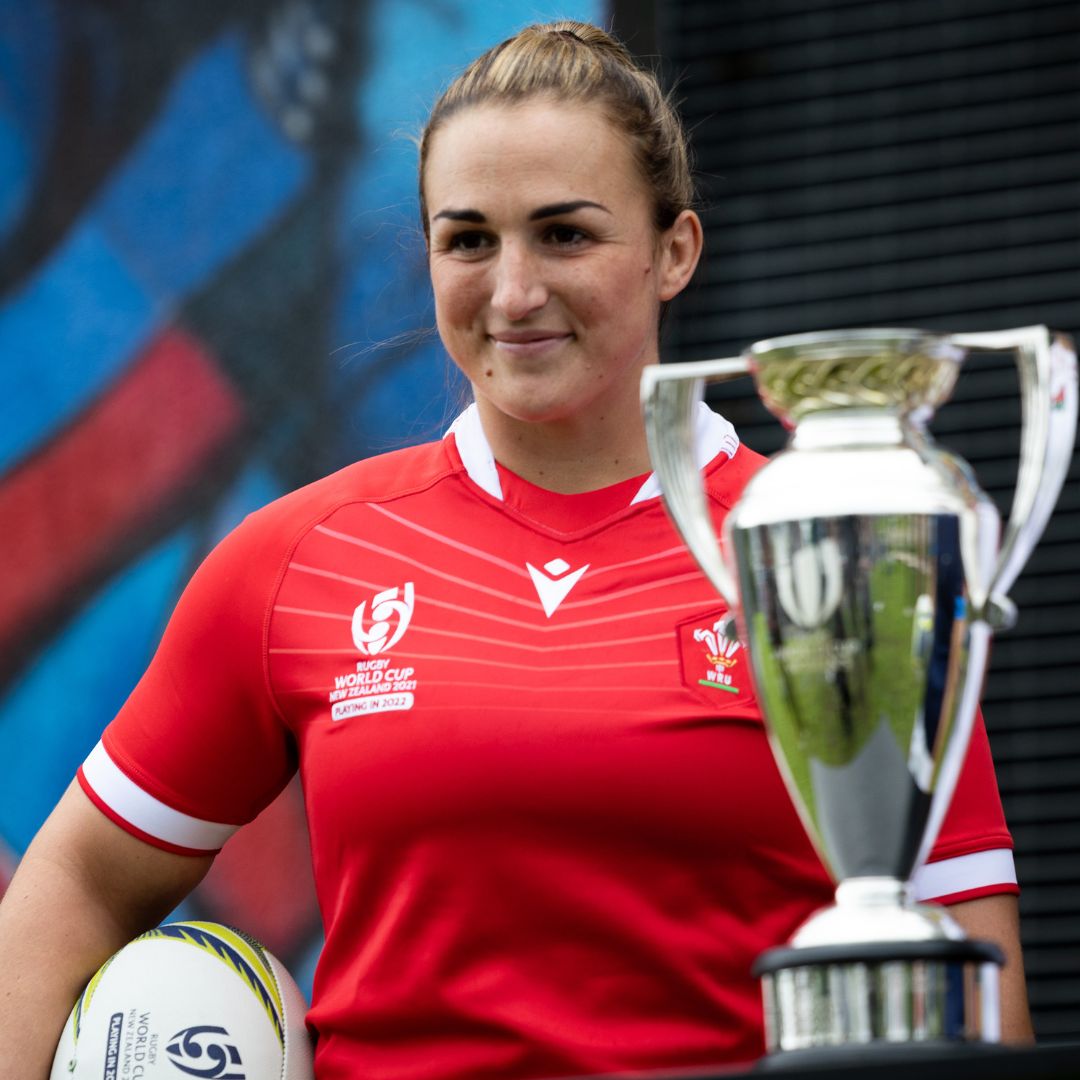 Lady holding a rugby ball and a trophy