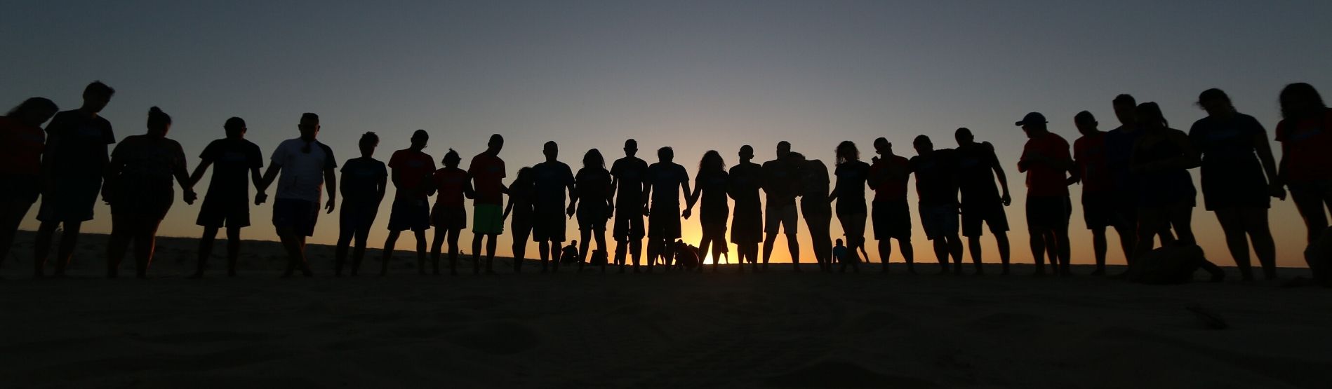 line of people holding hands in a sunset