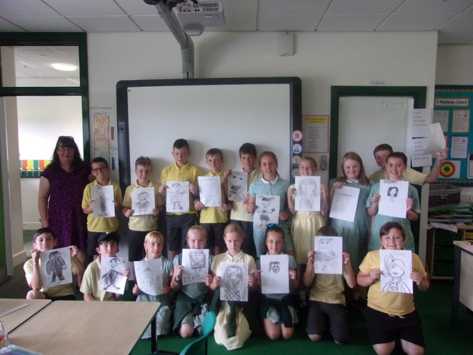Image of a classroom of children presenting drawings that they have made. 