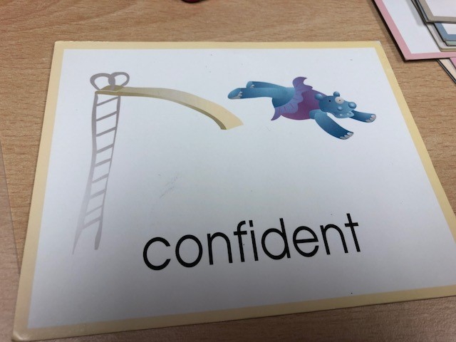 Shows a cartoon hippo jumping from a slide with the word 'confident' underneath. 