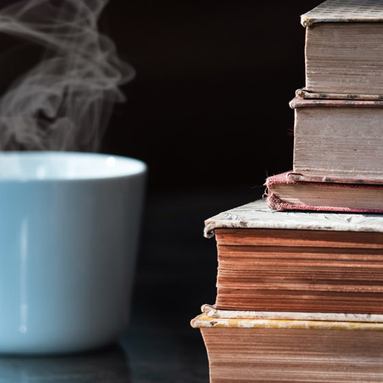 A stack of books next to a cup of coffee