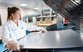 Women working with a sheet of steel in the lab
