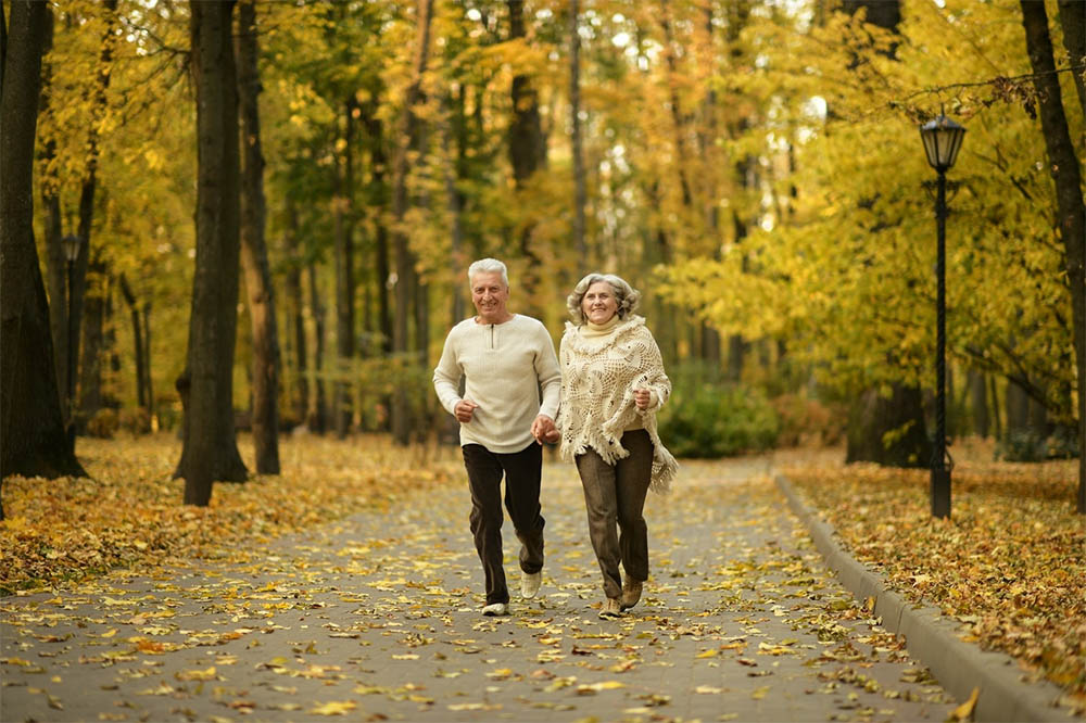 Older man and woman holding hands and walking 