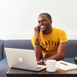 An image of a student making a phone call sitting by a laptop.