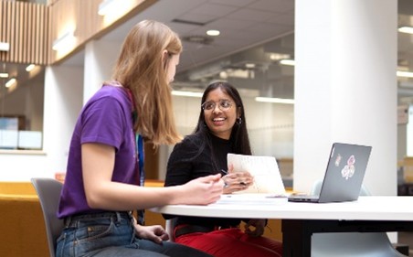 An image of two students studying and chatting on Bay Campus.