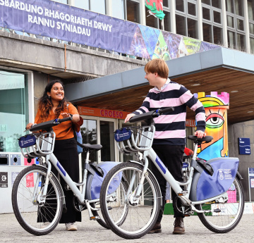 An image of two students with Swansea University bikes on Singleton Campus.