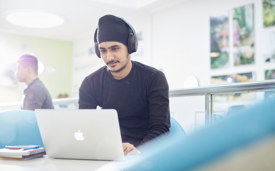 student wearing headphones using a laptop