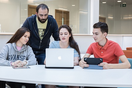 Four students looking at a laptop