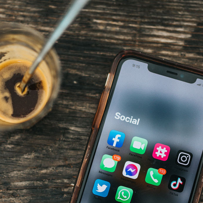 Image of a phone with social media apps and a glass of coffee