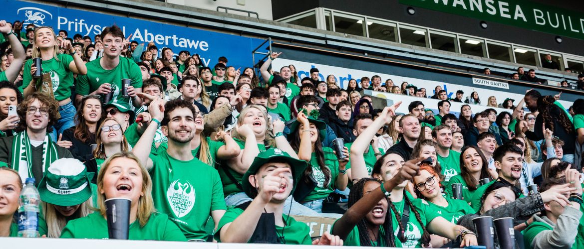 Students at the Liberty Stadium waving Sport Swansea flags during Varsity. 