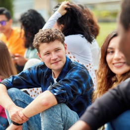 Delwedd o grŵp o fyfyrwyr yn eistedd y tu allan ar risiau ar Gampws Singleton.