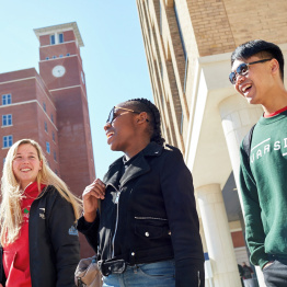 Delwedd o dri myfyrwraig yn cerdded heibio Twr y Cloc ar Gaerdydd Bay Campus.