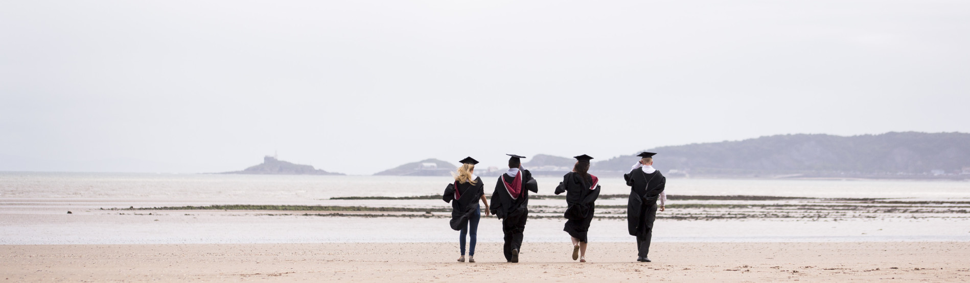 students walking across the beach