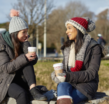 two girls having coffee on the grounds of a park