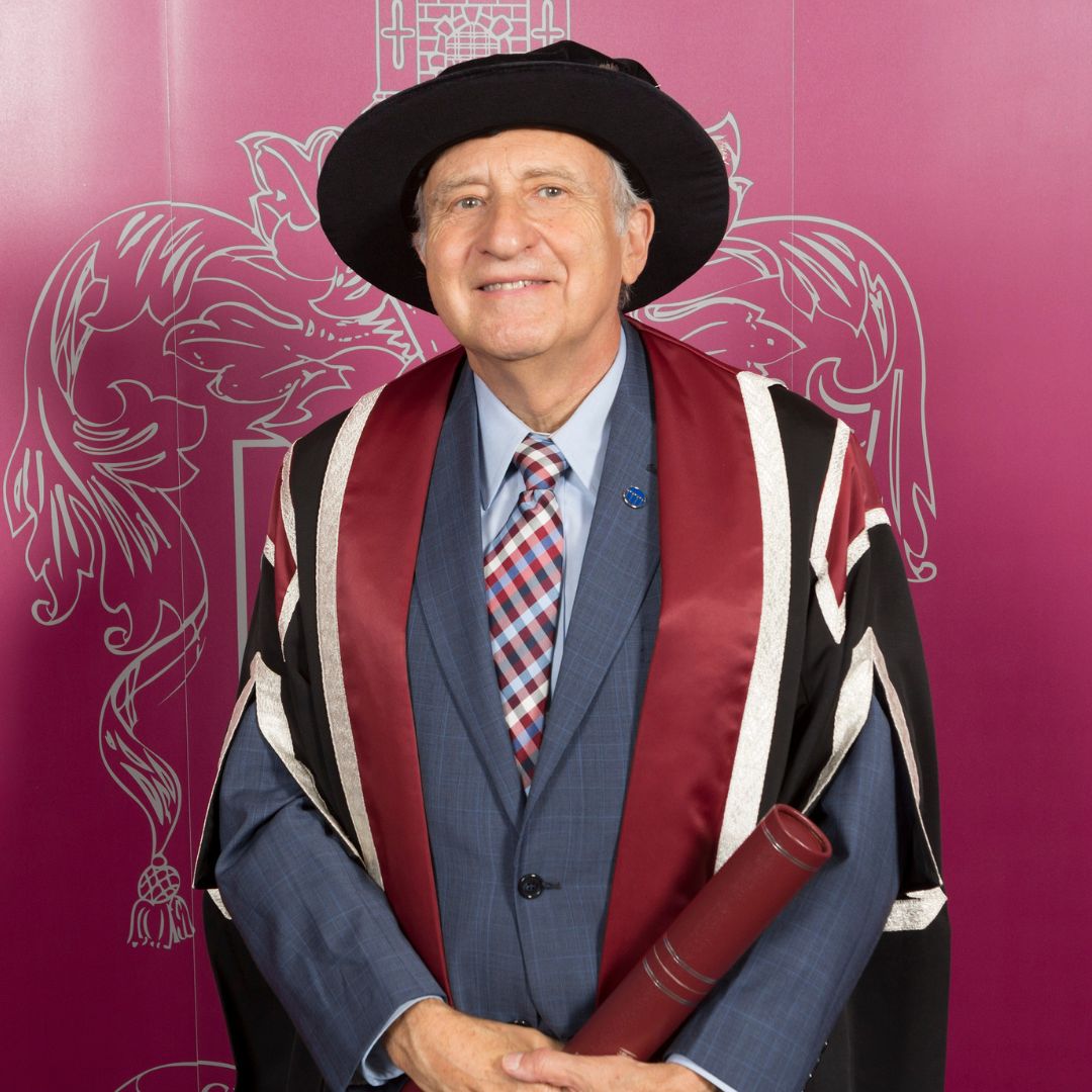 Dyn yn gwisgo gwisg graddio yn paratoi i gael llun